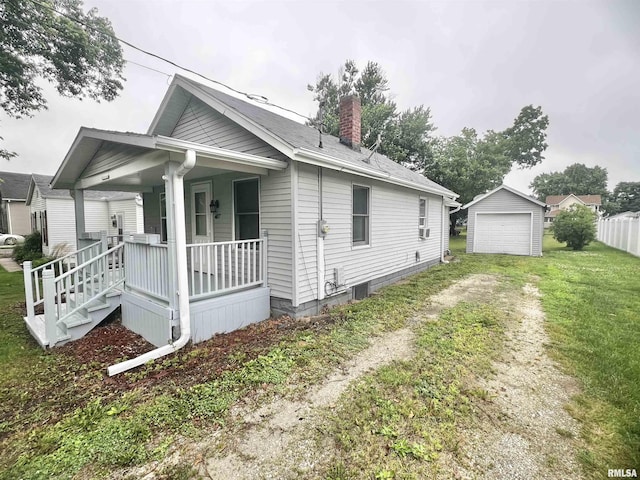407 E Depot St, Knoxville, IL 61448 - view of side of property featuring a porch, a chimney, a detached garage, an outbuilding, and dirt driveway