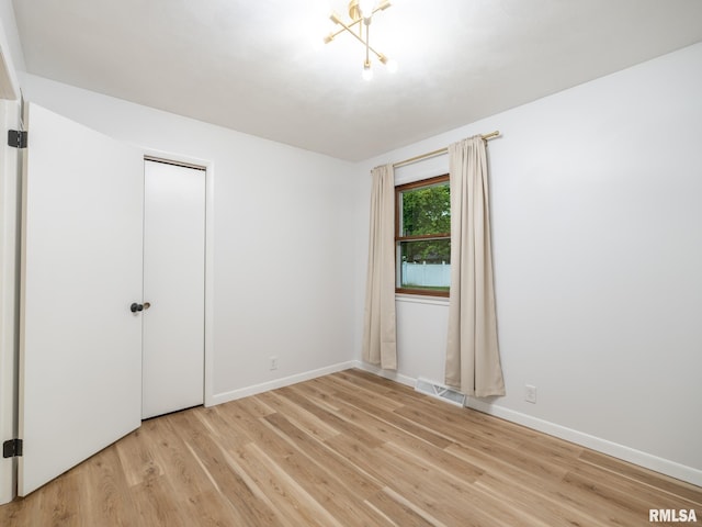 410 Stout Dr, Mackinaw, IL 61755 - spare room featuring light wood-type flooring and a chandelier