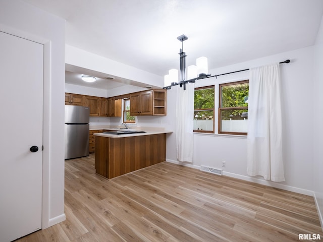 410 Stout Dr, Mackinaw, IL 61755 - kitchen featuring freestanding refrigerator, open shelves, brown cabinetry, a peninsula, and a chandelier