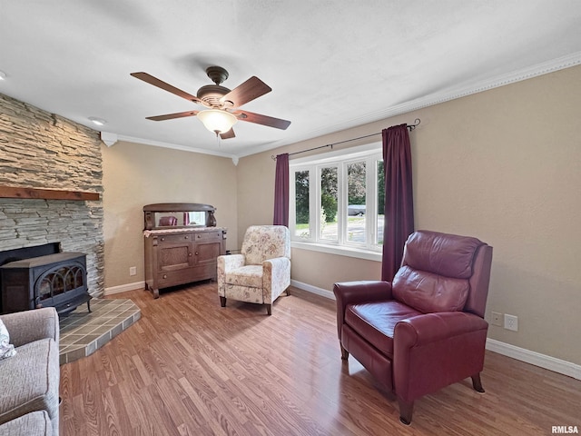490 Oak Point Rd, Metamora, IL 61548 - sitting room with a wood stove, wood finished floors, a ceiling fan, and ornamental molding