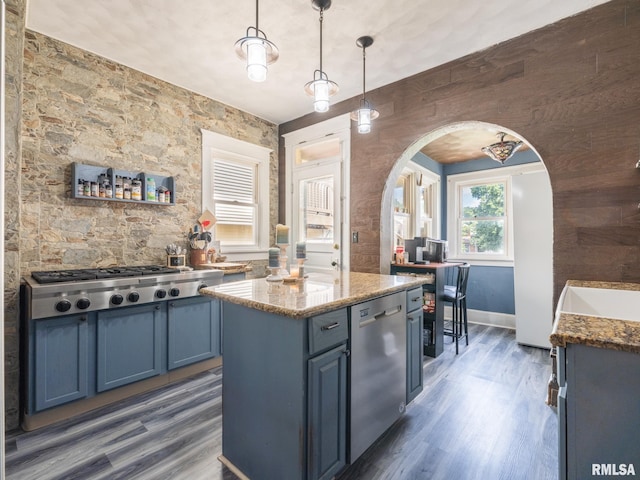 405 Washington St, Pekin, IL 61554 - kitchen featuring stainless steel appliances, blue cabinets, arched walkways, dark wood-style floors, and light stone counters
