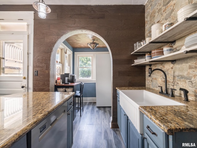 405 Washington St, Pekin, IL 61554 - kitchen with open shelves, arched walkways, blue cabinetry, wood finished floors, and stainless steel dishwasher