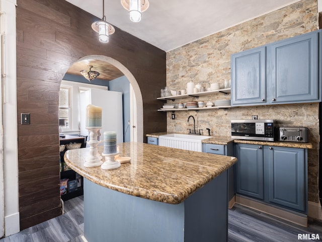 405 Washington St, Pekin, IL 61554 - kitchen with stainless steel microwave, blue cabinetry, arched walkways, and dark wood-type flooring