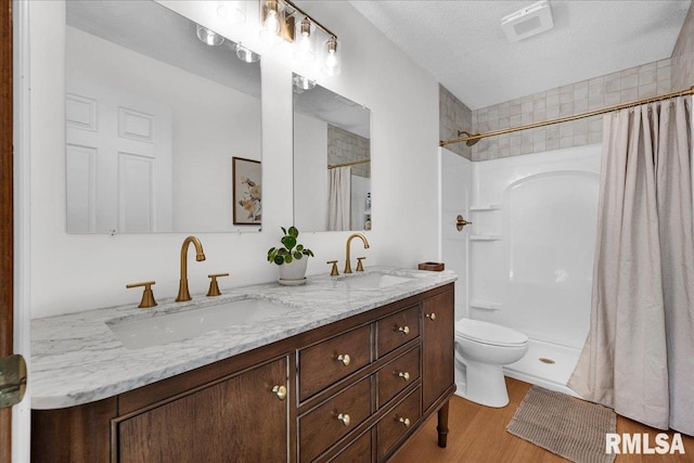 1208 S Adams Rd, Eureka, IL 61530 - bathroom with double vanity, wood finished floors, a shower with curtain, and a textured ceiling