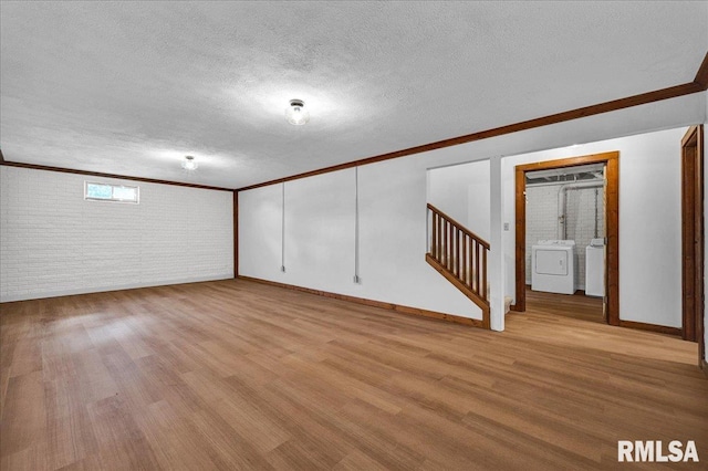 1208 S Adams Rd, Eureka, IL 61530 - basement featuring washer and clothes dryer, brick wall, crown molding, light wood-style floors, and stairs