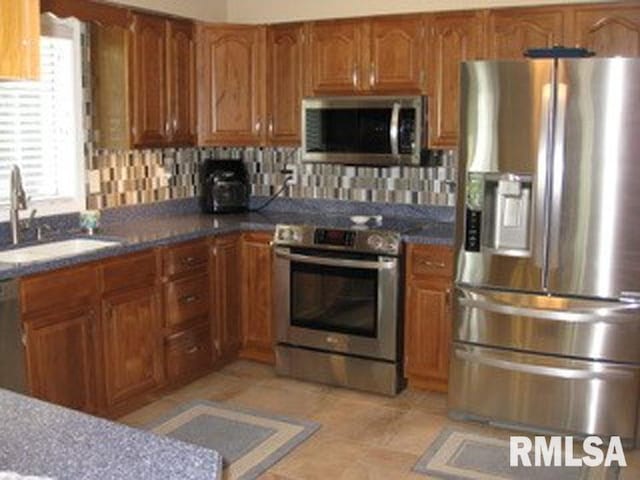 17215 N Mangold Rd, Edelstein, IL 61526 - kitchen featuring stainless steel appliances, brown cabinetry, backsplash, and dark countertops