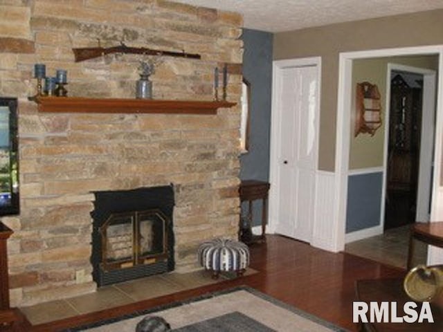 17215 N Mangold Rd, Edelstein, IL 61526 - living area with a stone fireplace, wood finished floors, and a textured ceiling