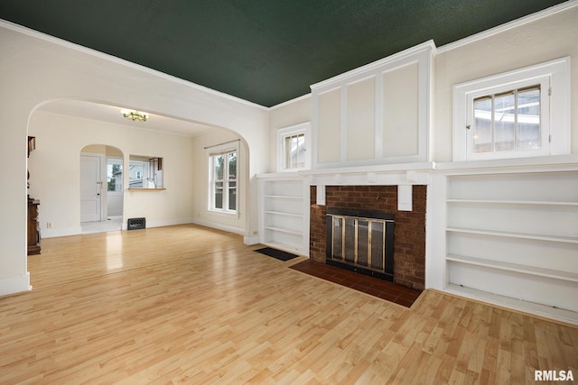 2017 W Laura Ave, West Peoria, IL 61604 - unfurnished living room with arched walkways, wood finished floors, ornamental molding, built in features, and a brick fireplace
