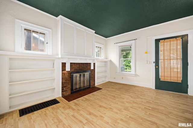 2017 W Laura Ave, West Peoria, IL 61604 - unfurnished living room featuring wood finished floors, a fireplace, built in features, and ornamental molding
