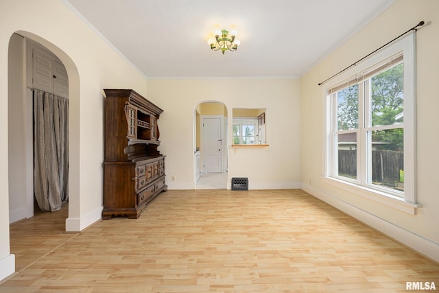 2017 W Laura Ave, West Peoria, IL 61604 - unfurnished living room featuring arched walkways, light wood-type flooring, ornamental molding, and plenty of natural light