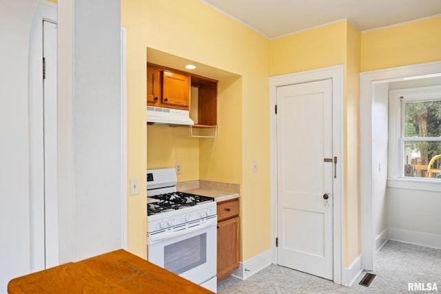 2017 W Laura Ave, West Peoria, IL 61604 - kitchen featuring white gas stove, under cabinet range hood, brown cabinetry, and light countertops