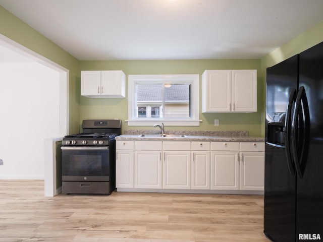 1108 Mechanic St, Pekin, IL 61554 - kitchen featuring black fridge, stainless steel gas range oven, white cabinets, light wood-style floors, and light countertops