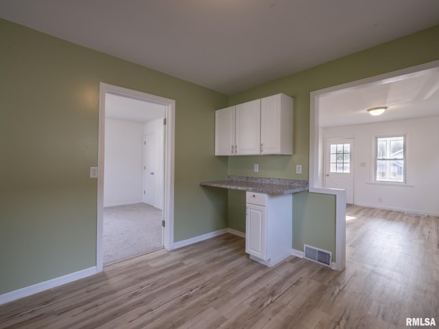 1108 Mechanic St, Pekin, IL 61554 - kitchen featuring light wood-style flooring, built in study area, white cabinetry, and light countertops