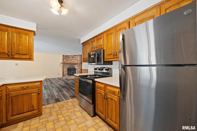 112 Iron Bark Ct, East Peoria, IL 61611 - kitchen with appliances with stainless steel finishes, light countertops, brown cabinetry, and a fireplace
