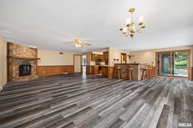 112 Iron Bark Ct, East Peoria, IL 61611 - unfurnished living room featuring a ceiling fan, dark wood-style flooring, wainscoting, a fireplace, and a chandelier