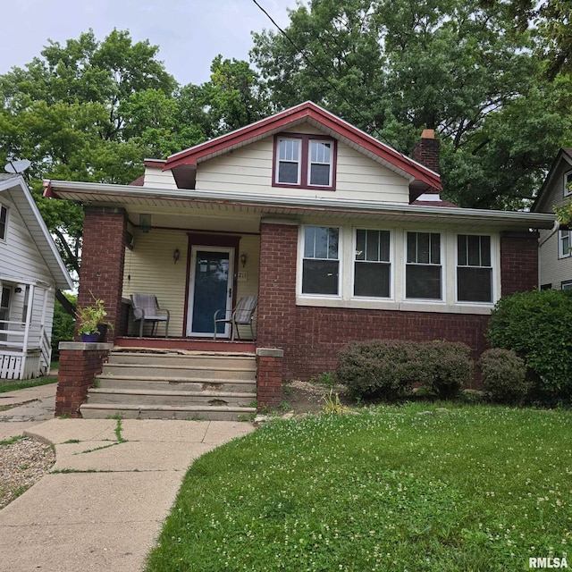 211 E Frye Ave, Peoria, IL 61603 - bungalow with covered porch, brick siding, a chimney, and a front yard