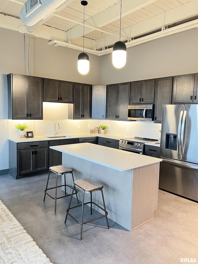 1001 SW Adams St Unit 102, Peoria, IL 61602 - kitchen featuring appliances with stainless steel finishes, concrete floors, a high ceiling, a kitchen bar, and a kitchen island