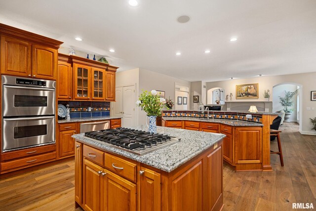 88 Waldheim Rd, Morton, IL 61550 - kitchen with stainless steel appliances, a kitchen island with sink, arched walkways, a kitchen bar, and dark wood-style floors
