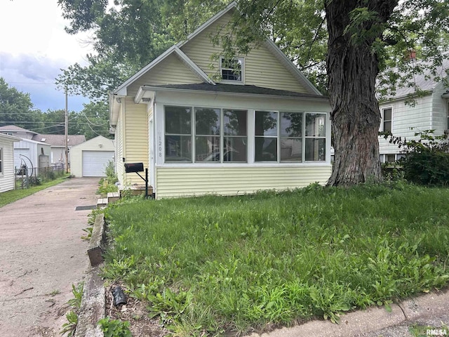 1208 S 13th St, Pekin, IL 61554 - view of front of home featuring a detached garage, concrete driveway, an outdoor structure, and a sunroom