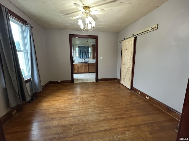 1208 S 13th St, Pekin, IL 61554 - unfurnished room with a barn door, light wood-type flooring, a ceiling fan, and healthy amount of natural light