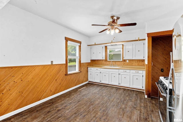 1603 Willow St, Pekin, IL 61554 - kitchen featuring white gas stove, wooden walls, white cabinets, ceiling fan, and wainscoting