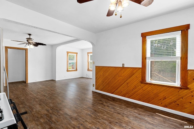 1603 Willow St, Pekin, IL 61554 - unfurnished living room featuring a ceiling fan, wooden walls, arched walkways, wood finished floors, and wainscoting