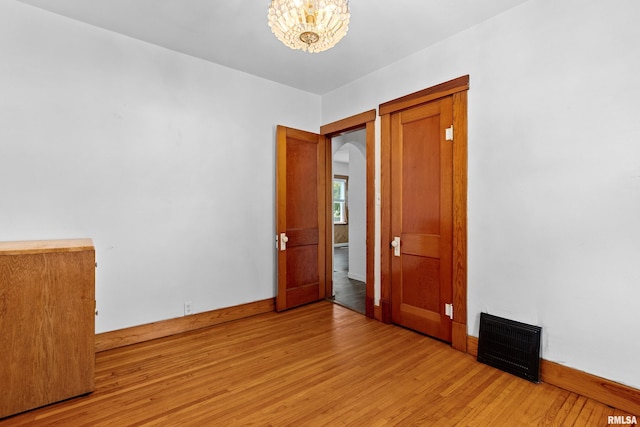 1603 Willow St, Pekin, IL 61554 - empty room featuring light wood-type flooring, arched walkways, and a chandelier