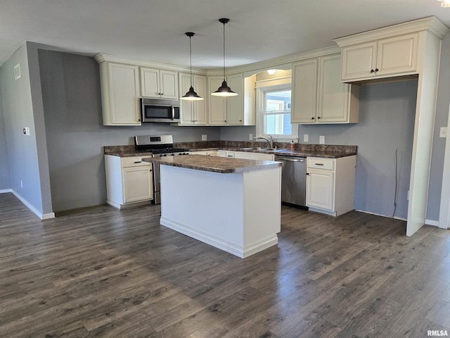 102 Conch Dr, La Harpe, IL 61450 - kitchen with stainless steel appliances, dark countertops, a center island, dark wood-type flooring, and decorative light fixtures