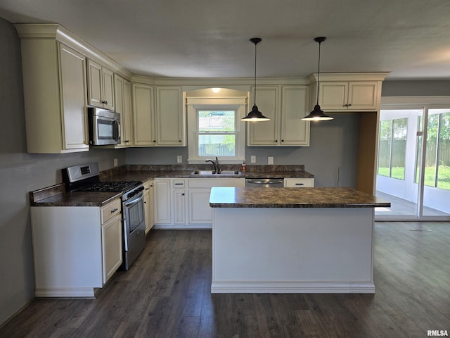 102 Conch Dr, La Harpe, IL 61450 - kitchen with appliances with stainless steel finishes, dark countertops, dark wood-type flooring, a center island, and pendant lighting