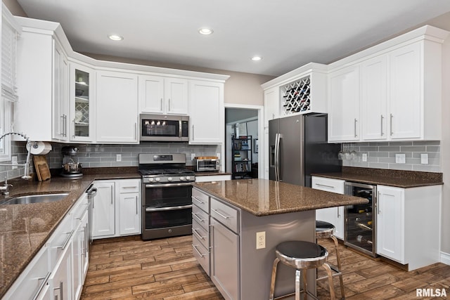 11 Lahood Ln, Washington, IL 61571 - kitchen featuring stainless steel appliances, beverage cooler, wood finished floors, a breakfast bar area, and white cabinetry