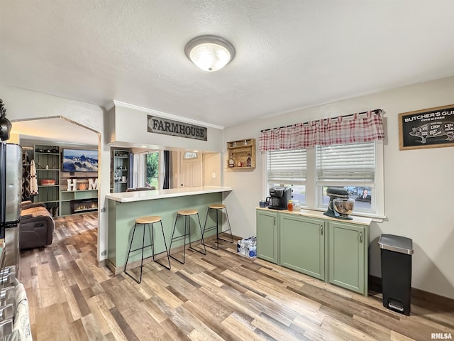 1506 S Capitol St, Pekin, IL 61554 - kitchen with green cabinets, light wood-style flooring, a kitchen breakfast bar, a textured ceiling, and plenty of natural light