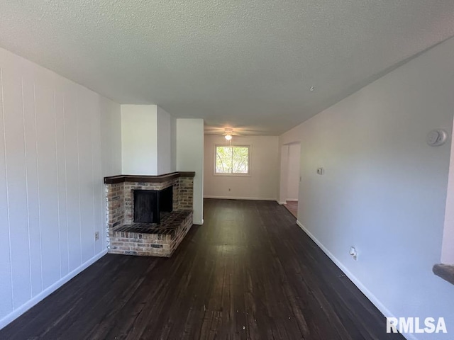 15 Cedar Dr, Macomb, IL 61455 - unfurnished living room with dark wood-type flooring, a brick fireplace, and a textured ceiling