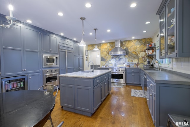 512 Hidden Ln, Peoria, IL 61614 - kitchen featuring appliances with stainless steel finishes, wall chimney range hood, dark wood-style floors, decorative light fixtures, and glass insert cabinets