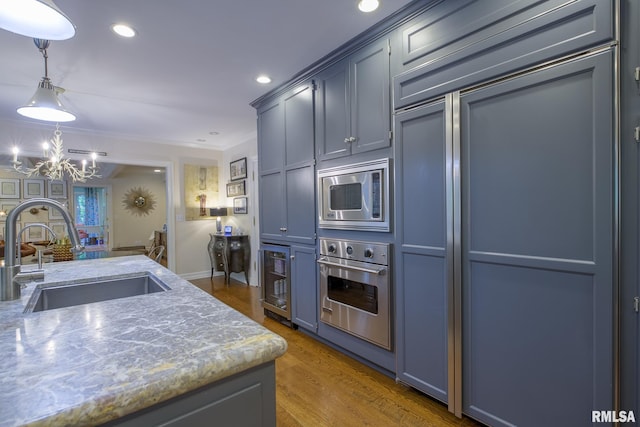 512 Hidden Ln, Peoria, IL 61614 - kitchen featuring built in appliances, a chandelier, wood finished floors, ornamental molding, and light stone countertops