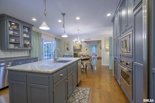 512 Hidden Ln, Peoria, IL 61614 - kitchen featuring appliances with stainless steel finishes, gray cabinetry, open floor plan, an island with sink, and glass insert cabinets