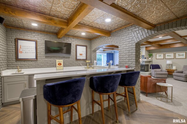 512 Hidden Ln, Peoria, IL 61614 - bar area with brick wall, beamed ceiling, arched walkways, a fireplace with raised hearth, and recessed lighting