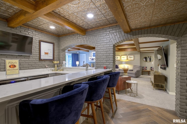 512 Hidden Ln, Peoria, IL 61614 - kitchen with arched walkways, beam ceiling, open floor plan, brick wall, and a breakfast bar area