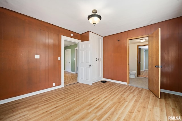 1013 N 2nd St, Pekin, IL 61554 - unfurnished bedroom featuring light wood-style flooring, wood walls, and ensuite bath
