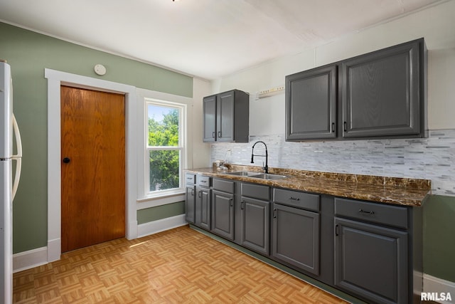 1013 N 2nd St, Pekin, IL 61554 - kitchen with decorative backsplash, gray cabinets, freestanding refrigerator, and dark stone counters