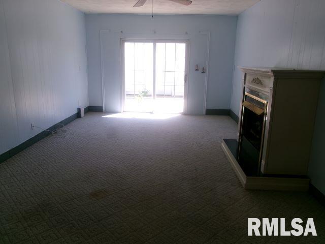 102 N Park Ave, Manito, IL 61546 - unfurnished living room featuring carpet floors, a ceiling fan, and a fireplace