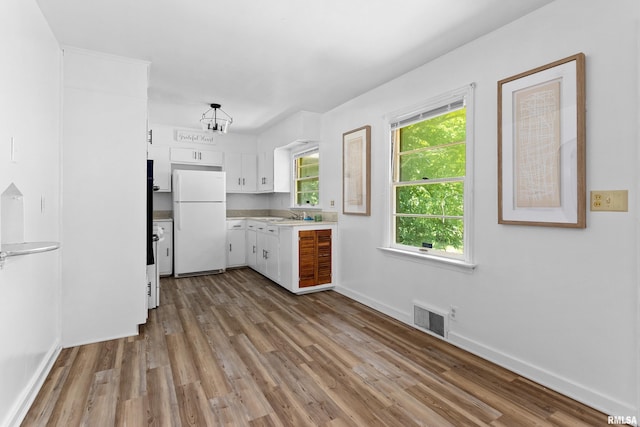 1726 N Pierson Dr, West Peoria, IL 61604 - kitchen with freestanding refrigerator, wood finished floors, white cabinets, light countertops, and a chandelier