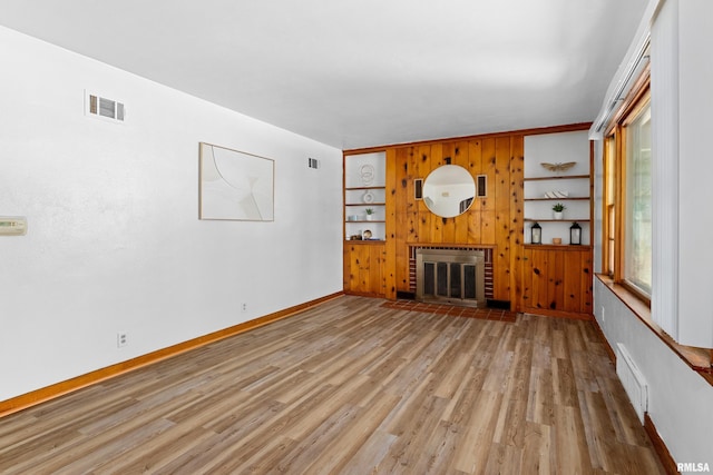 1726 N Pierson Dr, West Peoria, IL 61604 - unfurnished living room featuring light wood finished floors, a fireplace, built in shelves, and wooden walls