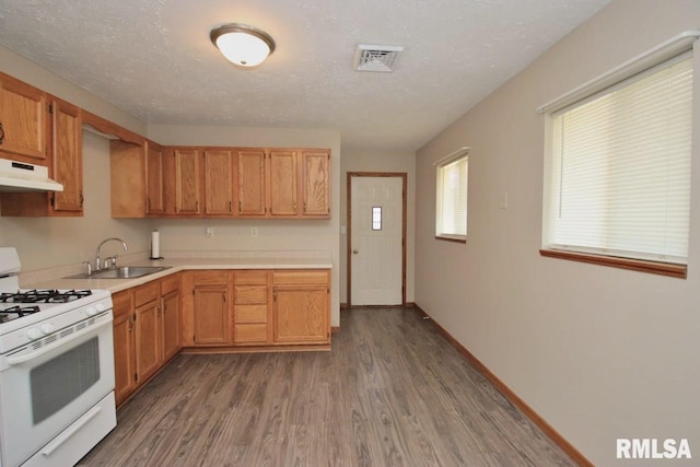 1409 Alton St, Pekin, IL 61554 - kitchen with white range with gas stovetop, light countertops, under cabinet range hood, and wood finished floors