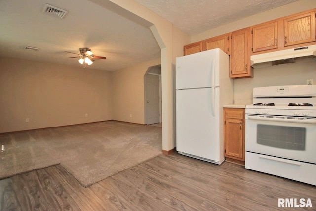1409 Alton St, Pekin, IL 61554 - kitchen featuring white appliances, under cabinet range hood, a ceiling fan, arched walkways, and wood finished floors