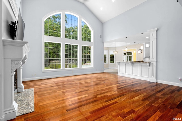 4851 Sheridan Rd, Groveland, IL 61535 - unfurnished living room with wood finished floors, a fireplace with flush hearth, and high vaulted ceiling