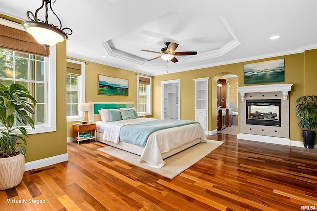 4851 Sheridan Rd, Groveland, IL 61535 - bedroom featuring a tray ceiling, wood finished floors, crown molding, arched walkways, and a multi sided fireplace