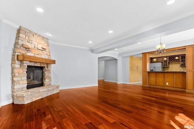 4851 Sheridan Rd, Groveland, IL 61535 - unfurnished living room featuring ornamental molding, arched walkways, a stone fireplace, wood finished floors, and a chandelier
