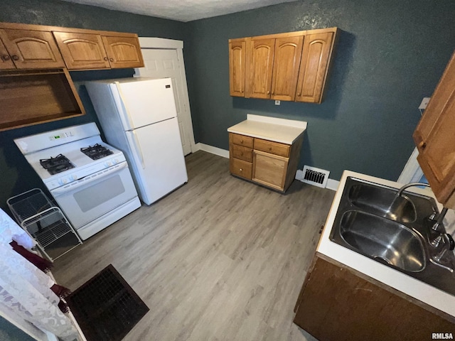 909 W Mcclure Ave, Peoria, IL 61604 - kitchen featuring white appliances, light wood-style floors, brown cabinetry, and light countertops
