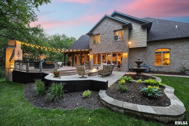 2204 W Pinnacle Dr, Dunlap, IL 61525 - back of property with brick siding, a wooden deck, a yard, a patio area, and a fire pit