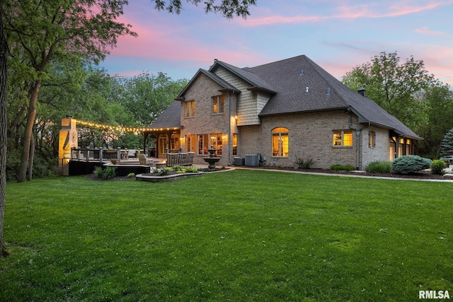 2204 W Pinnacle Dr, Dunlap, IL 61525 - back of house at dusk featuring brick siding, a yard, a wooden deck, and a shingled roof